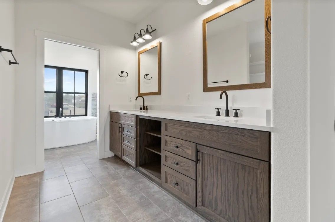 A bathroom with two sinks , two mirrors and a bathtub.