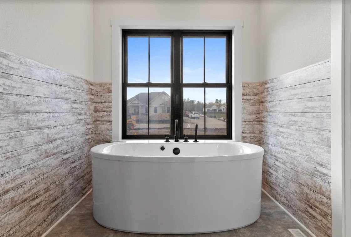 A bathtub in a bathroom next to a window.