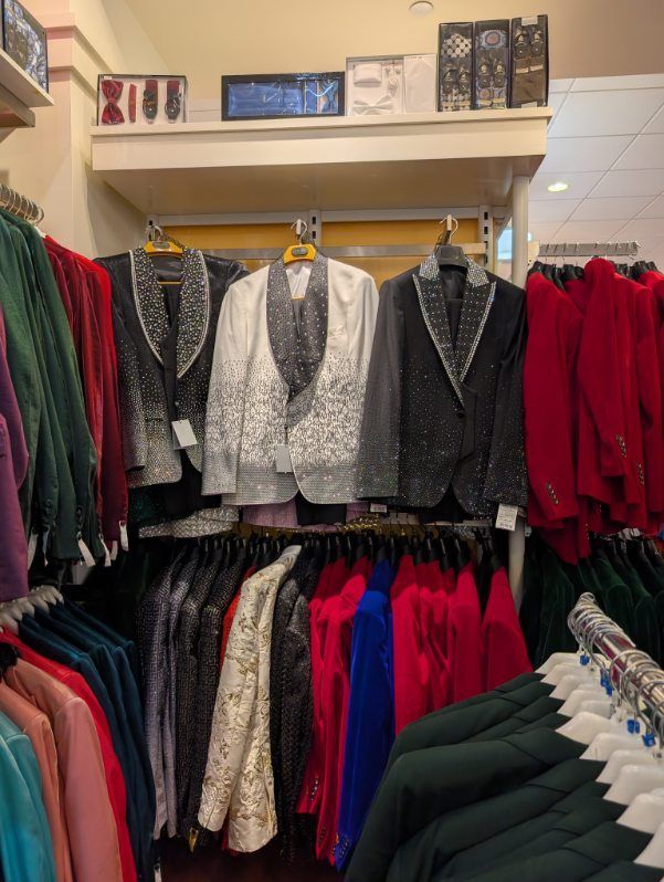 Clothing store rack with sequined jackets and colorful blazers.