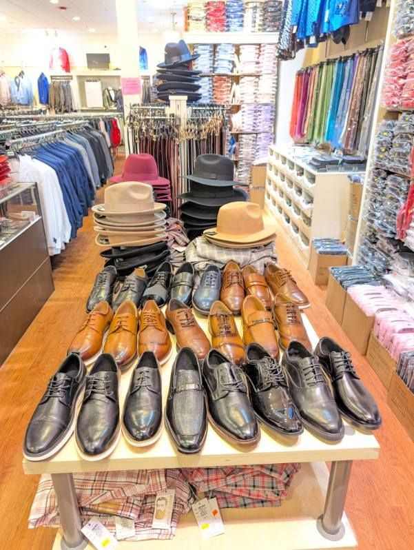 Men's clothing store with hats, shoes, shirts, and suits on display.