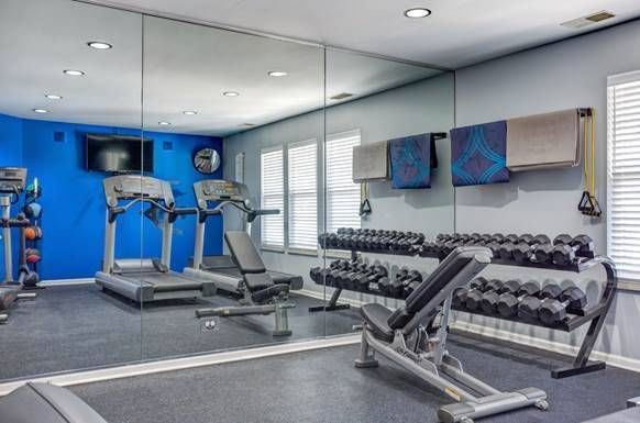 a gym with treadmills , dumbbells , a bench and a large mirror .