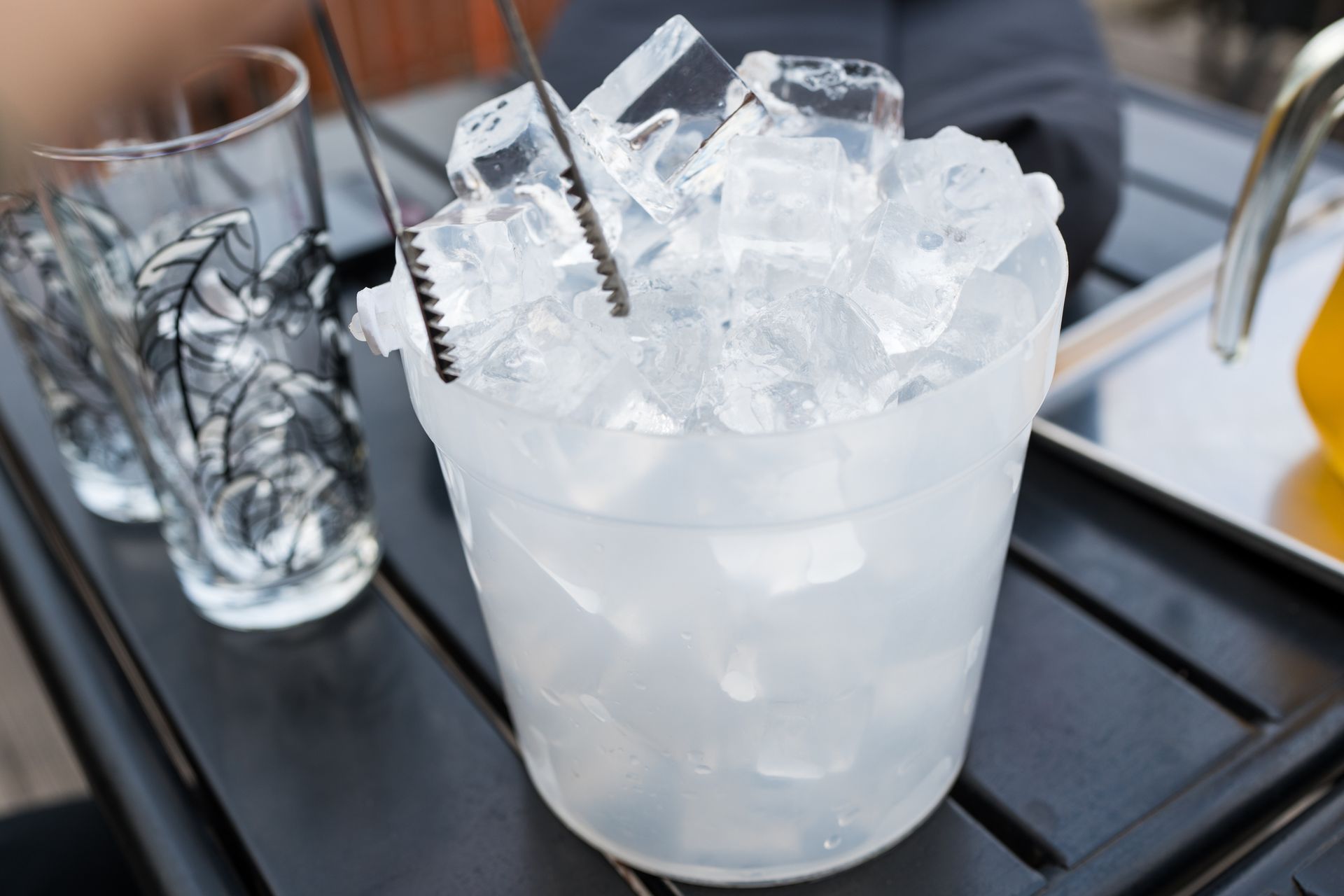 Man use stainless steel tongs keep ice into glass for drink. Man use stainless steel tongs keep ice into glass for drink.