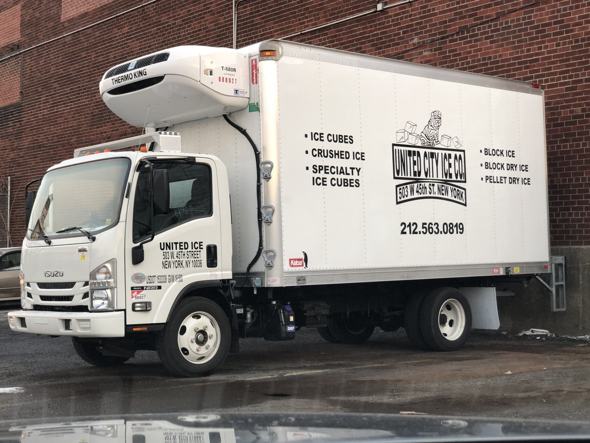 A white truck is parked in front of a brick building.