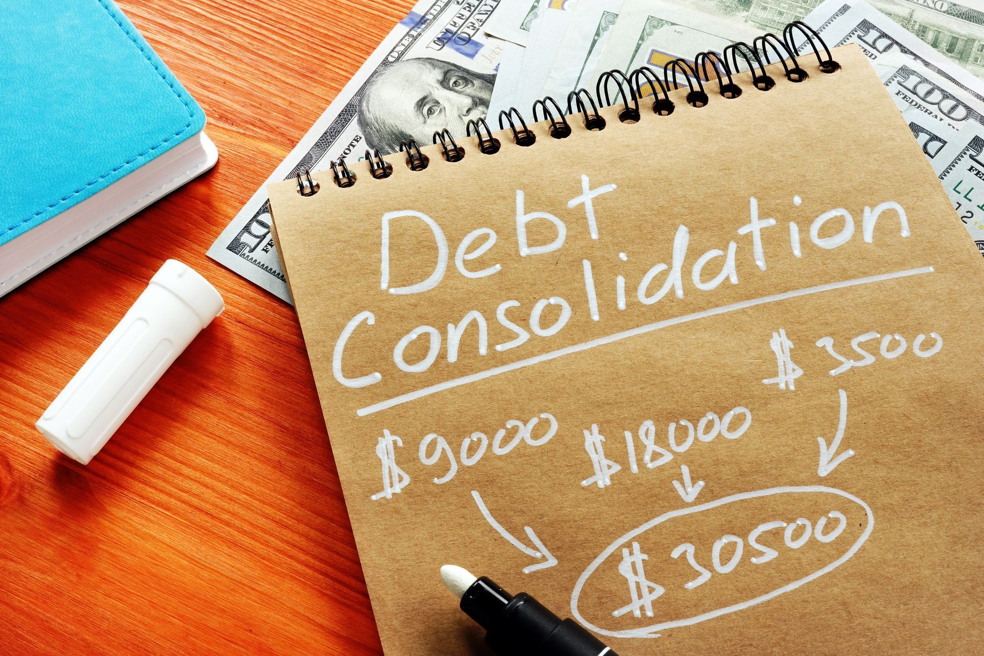 A debt consolidation title with written calculations and cash below the notebook.