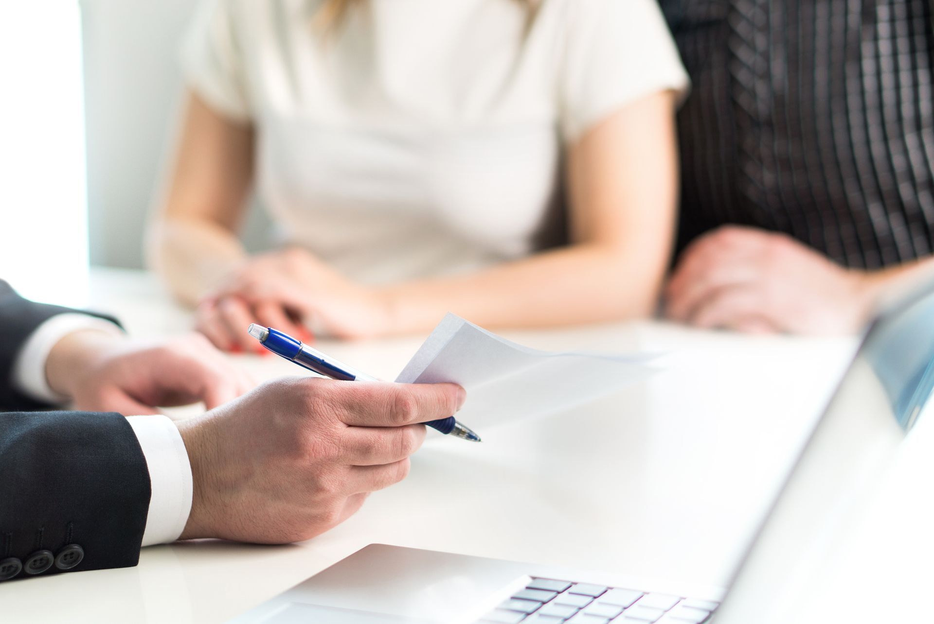 An attorney holding a document at a meeting with a couple, explaining debt consolidation to them.