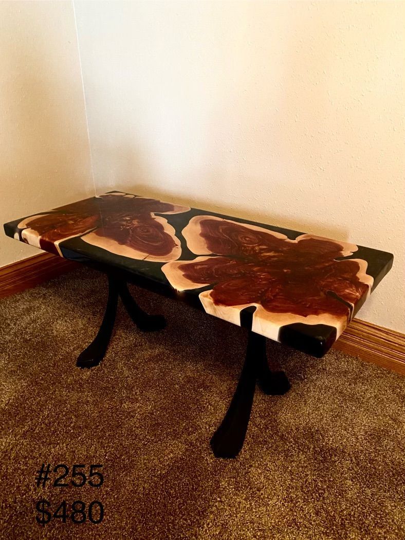 A coffee table made of wood and resin is sitting on a carpet in a room.
