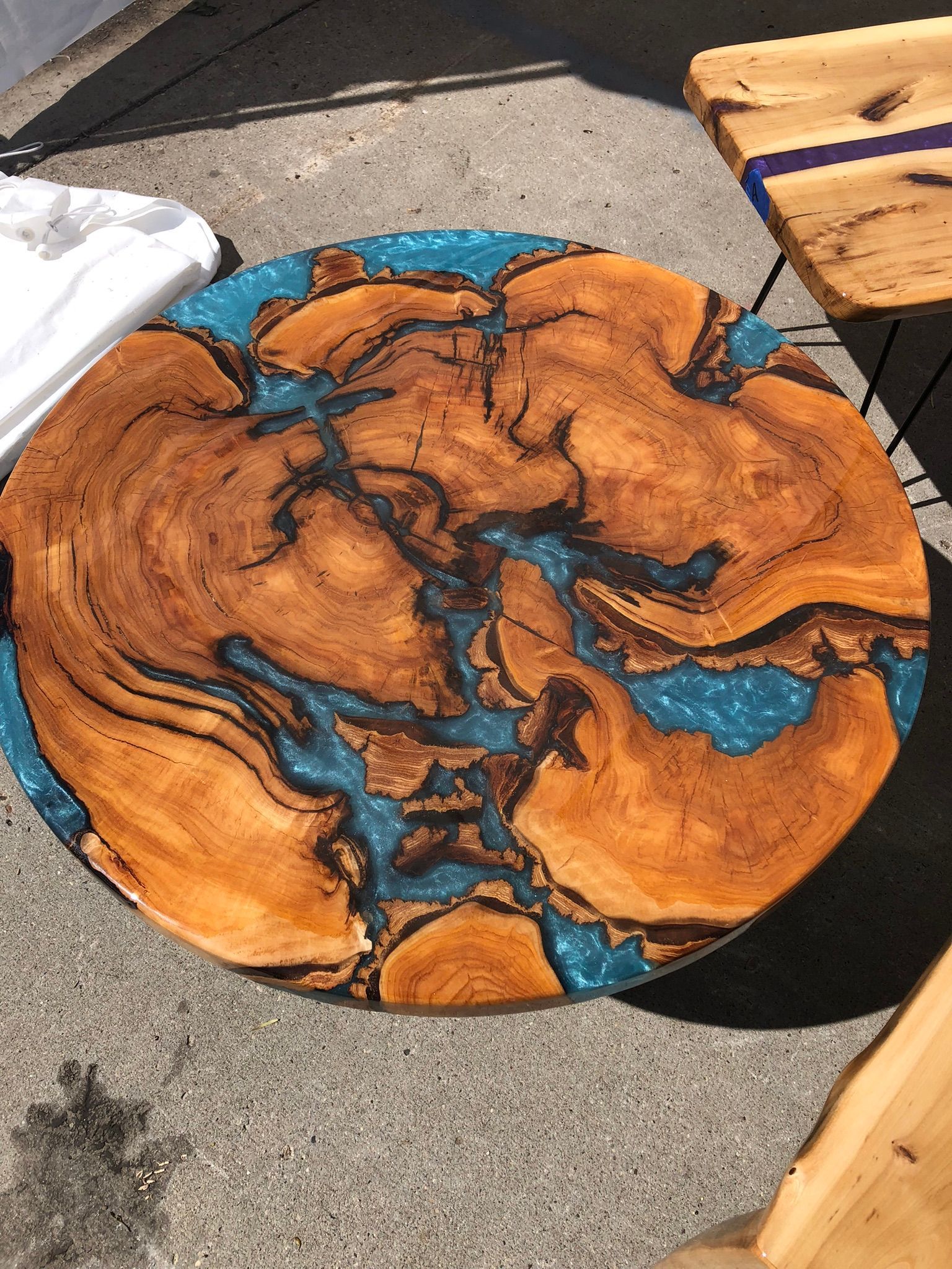 A wooden table with a blue resin top is sitting on the ground.