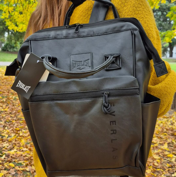 Una mujer con un suéter amarillo lleva una mochila negra Everlast.