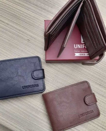 Hay dos carteras sobre una mesa de madera al lado de una caja.