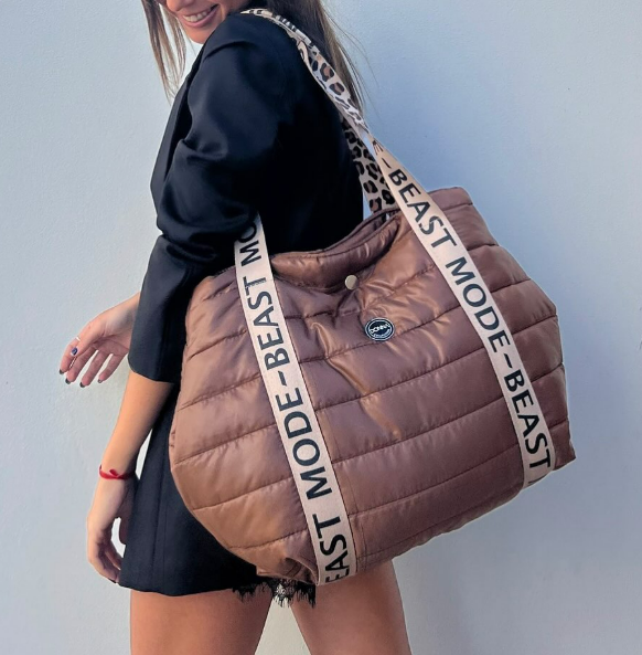 Una mujer lleva una bolsa marrón que dice modo bestia.