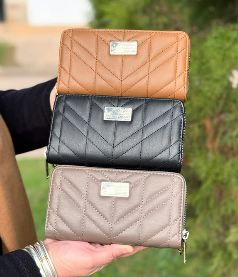 Una persona sostiene tres carteras en sus manos.