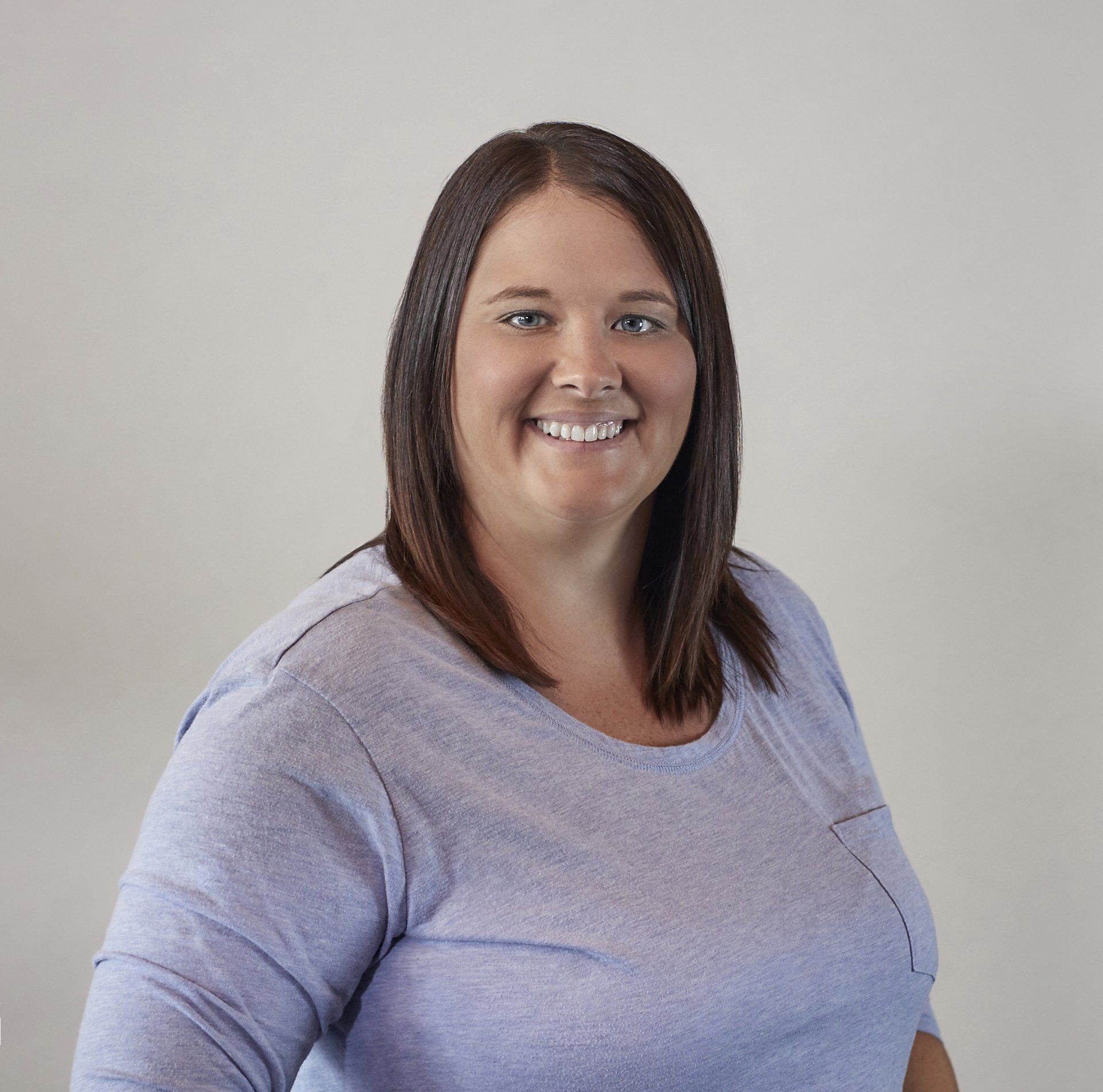 A woman in a purple shirt is smiling for the camera.