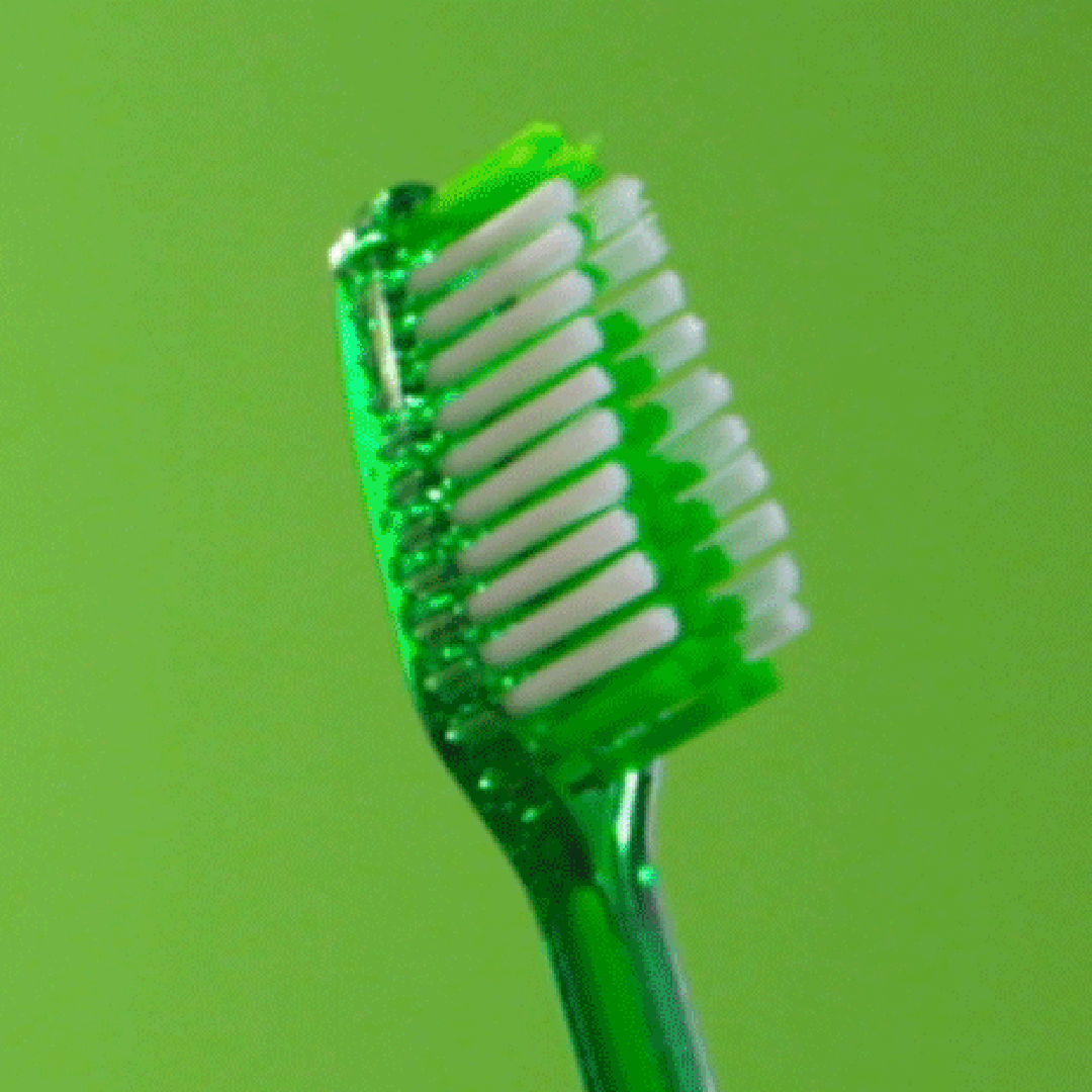 A green toothbrush with white bristles on a green background