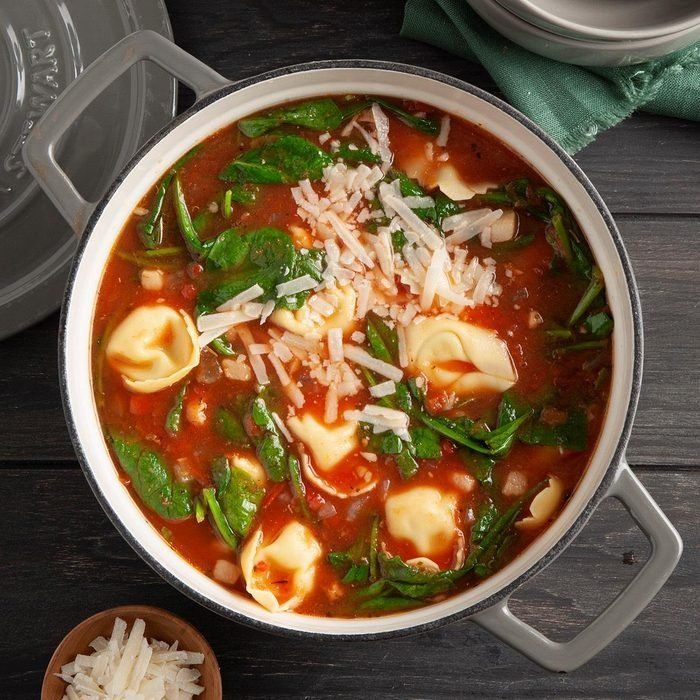 A pot of ravioli soup with spinach and cheese