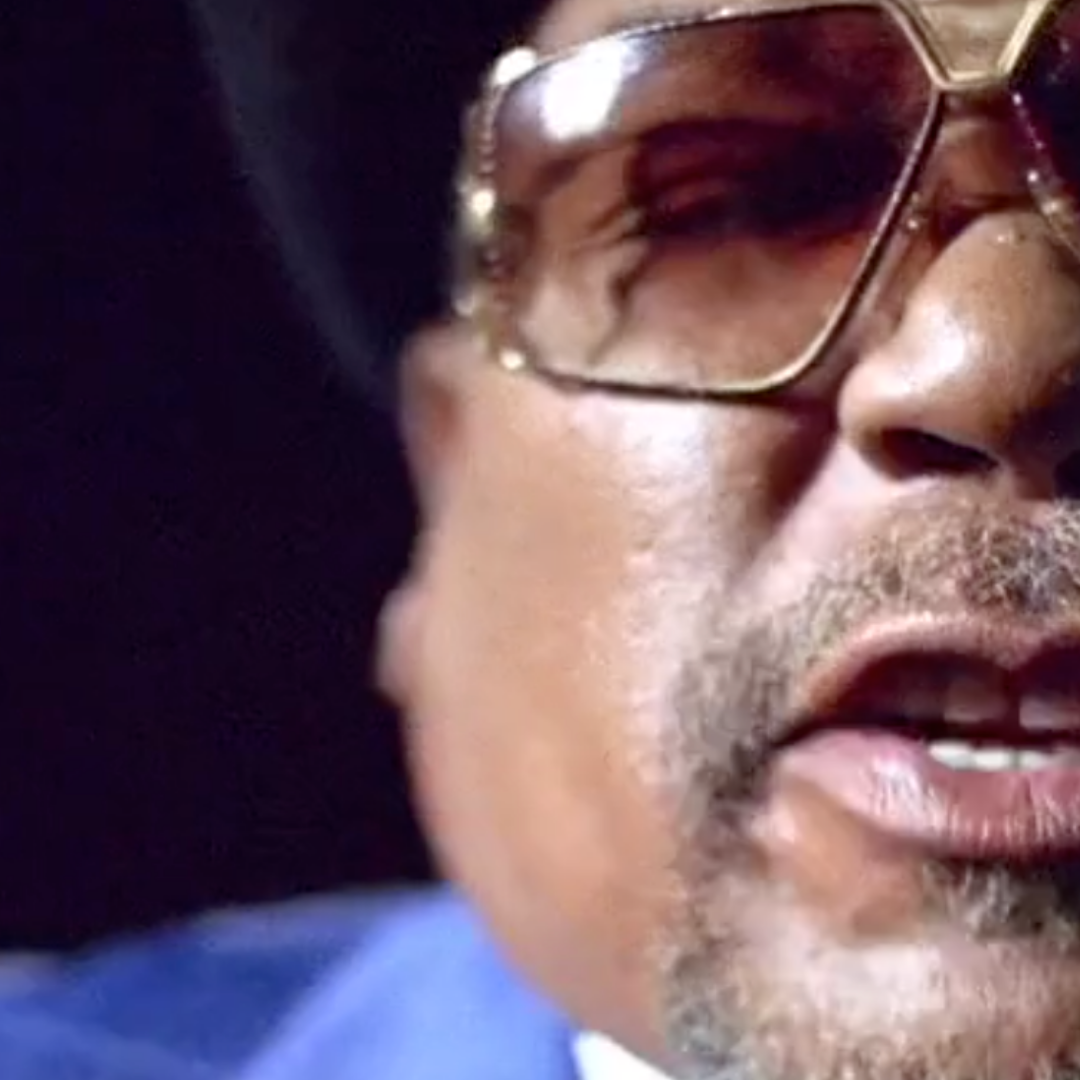 A close up of a man wearing sunglasses and a blue shirt