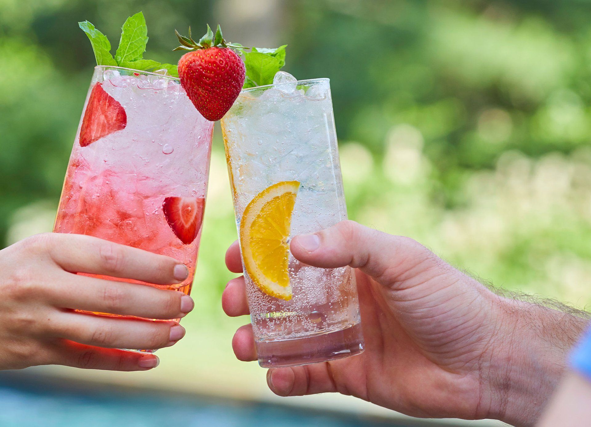 A man and a woman are toasting with two drinks.