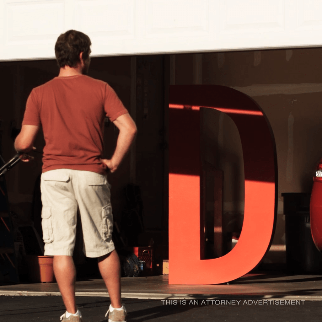 A man standing in front of a large red letter d