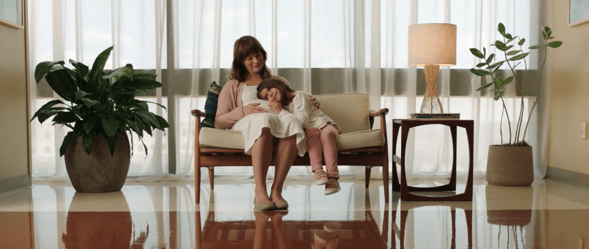 A woman and a child are sitting on a couch in a living room.