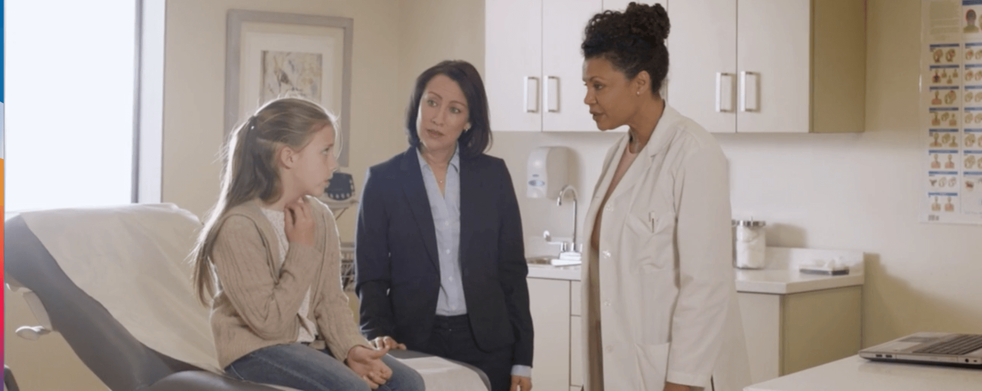 A doctor is talking to a little girl in a doctor 's office.