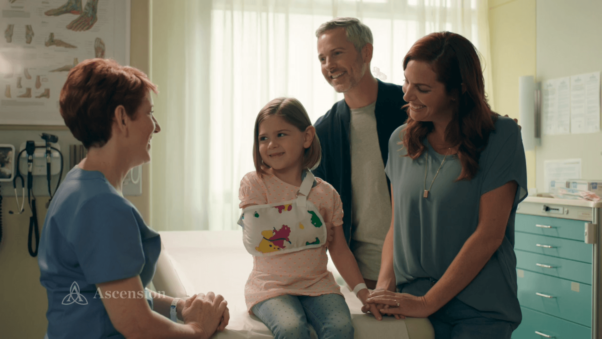 A little girl with a cast on her arm is sitting on a table talking to a doctor.