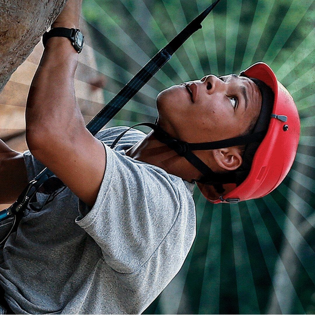 A man wearing a red helmet is climbing a rock