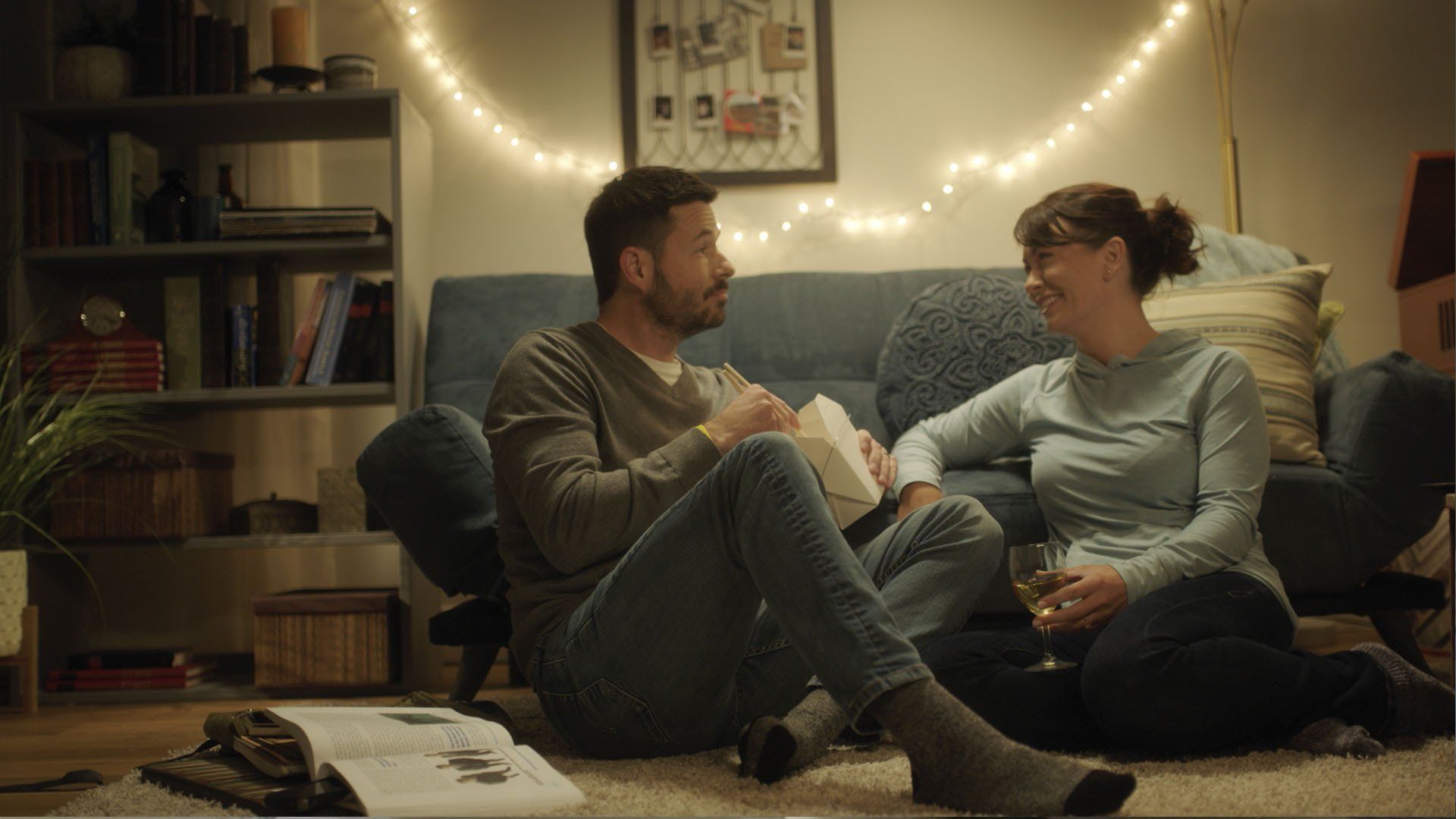 A man and a woman are sitting on the floor in a living room.
