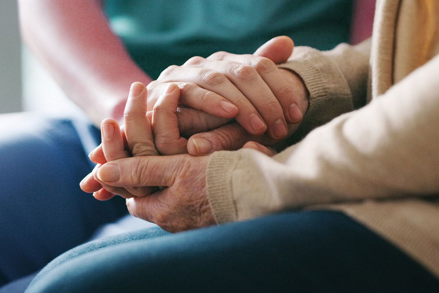 A man and a woman are holding hands while sitting on a couch.
