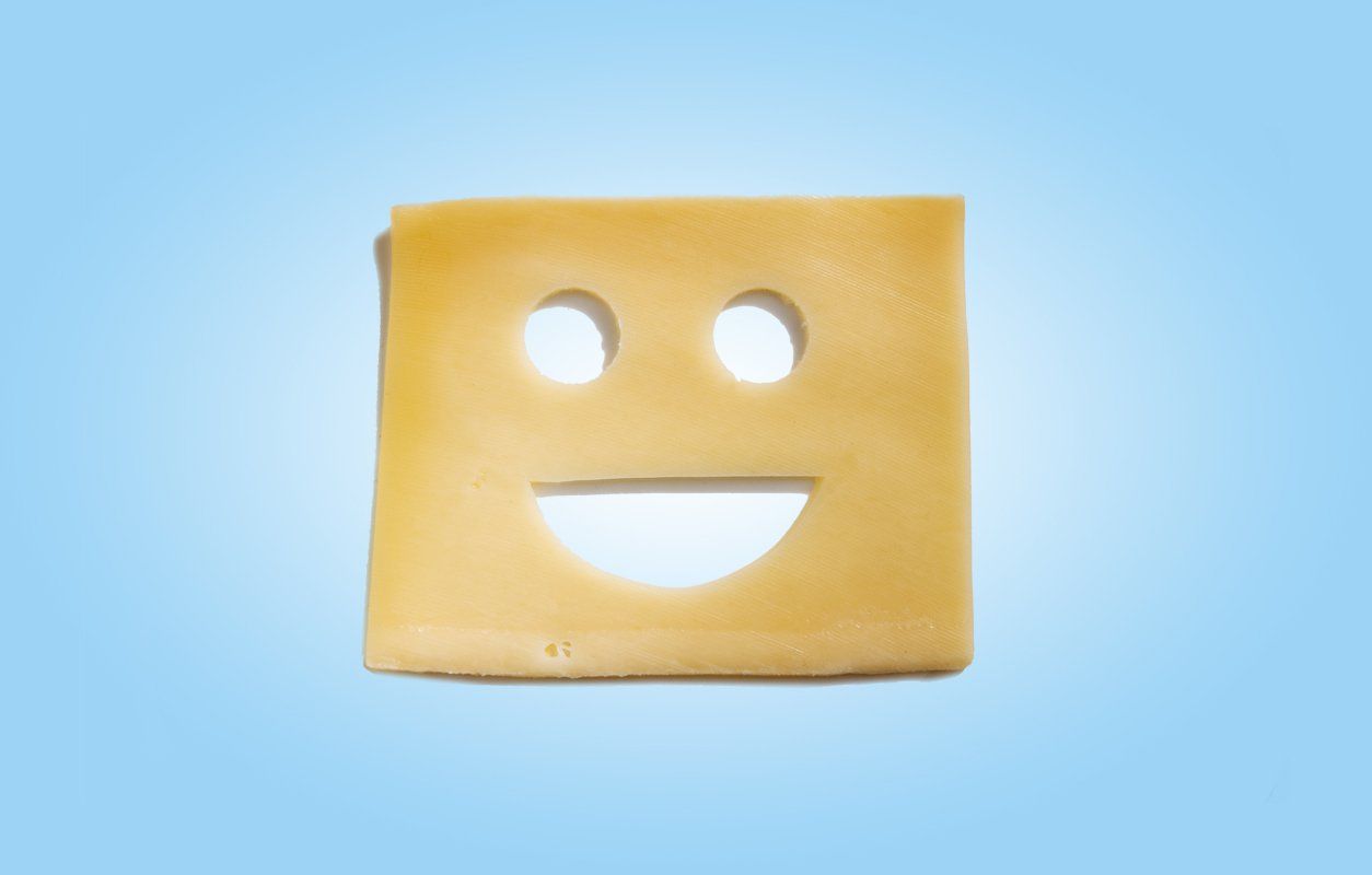 A piece of cheese with a smiley face cut out of it.