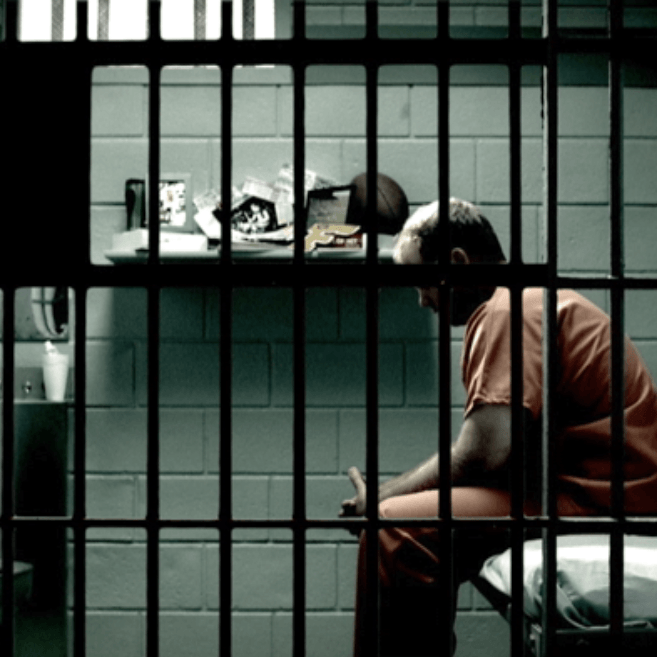 man sitting in a prison cell