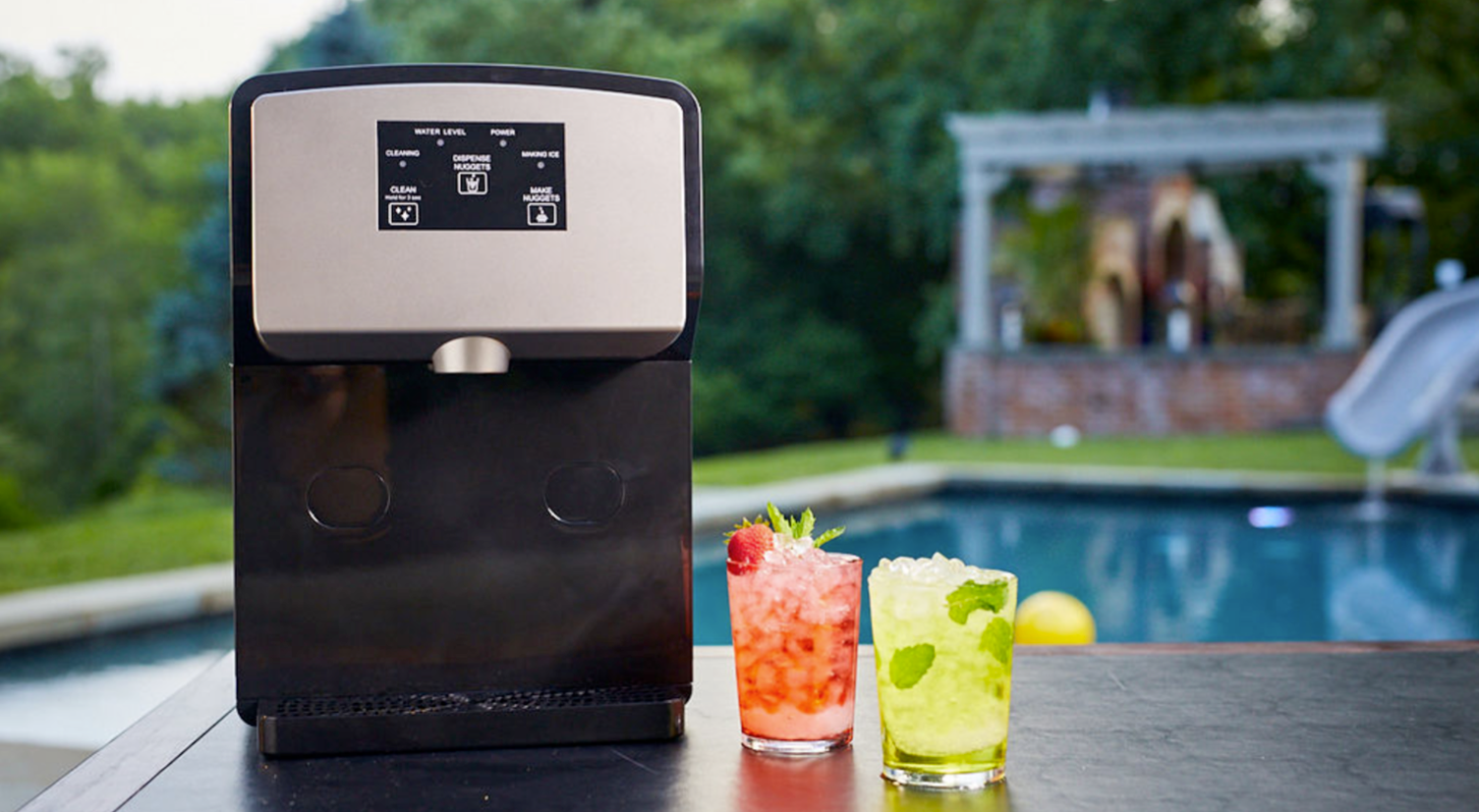 Two drinks are sitting on a table next to an ice machine.