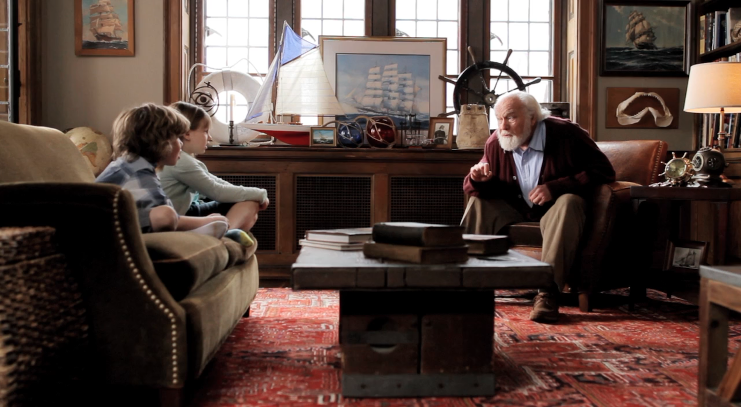 A man and two children are sitting in a living room talking to each other.