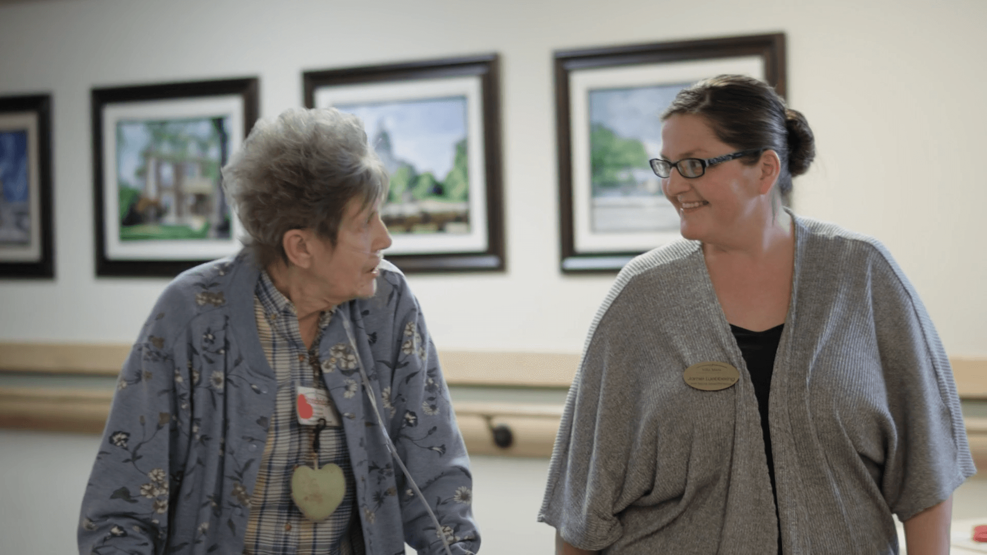 Two women are standing next to each other in a hallway.