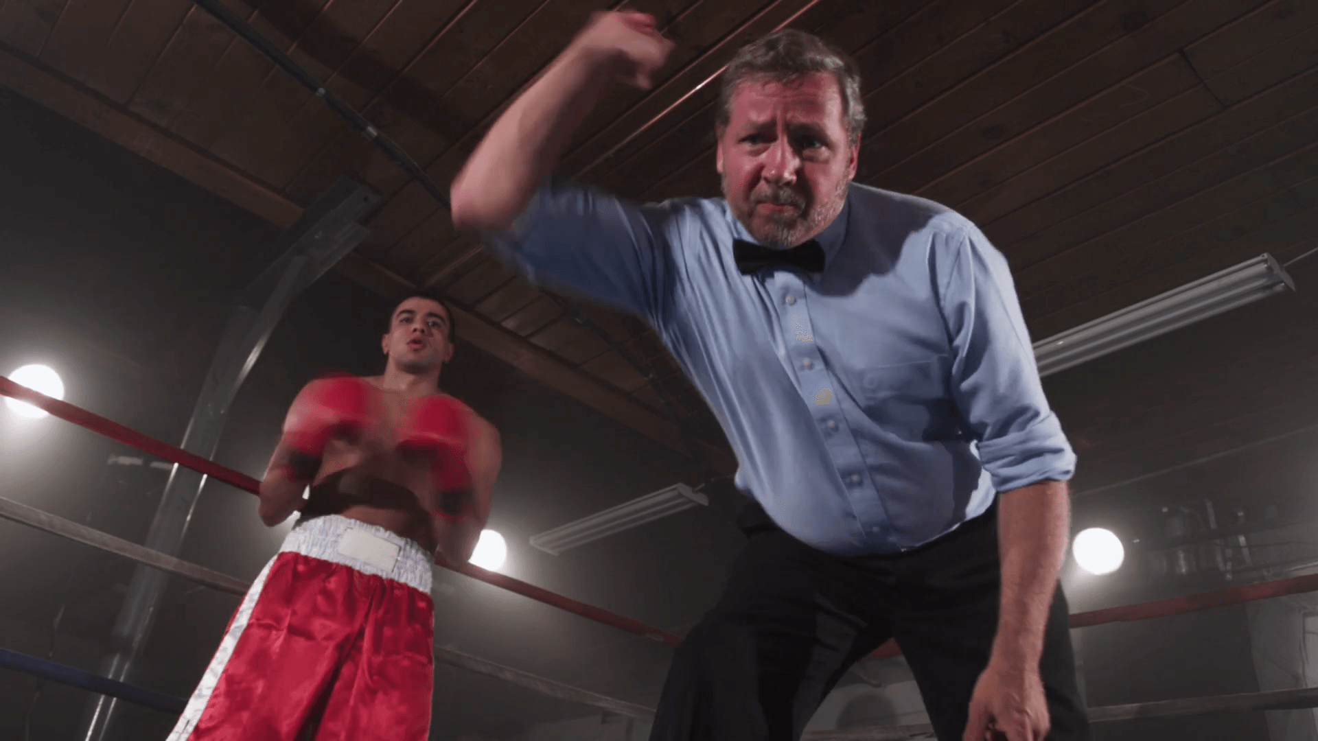 A referee is standing in the middle of a boxing ring.