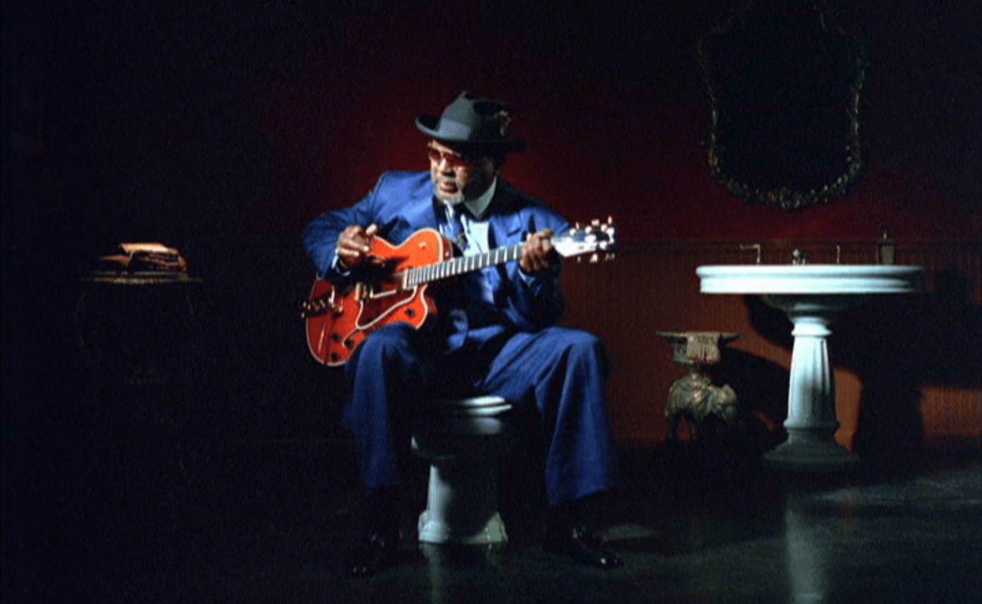 A man is sitting on a toilet playing a guitar