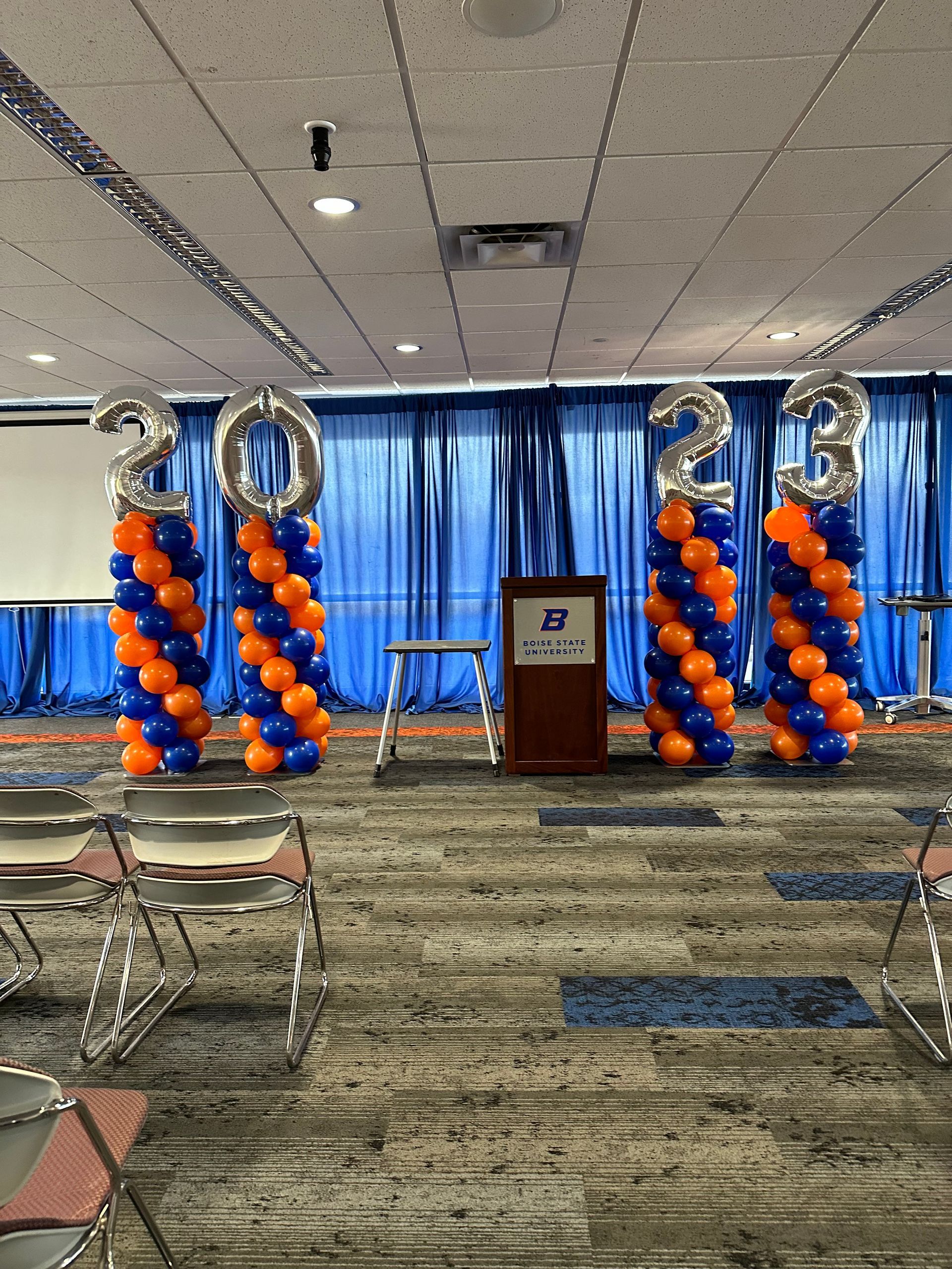 A room with a podium and balloons that say 2021