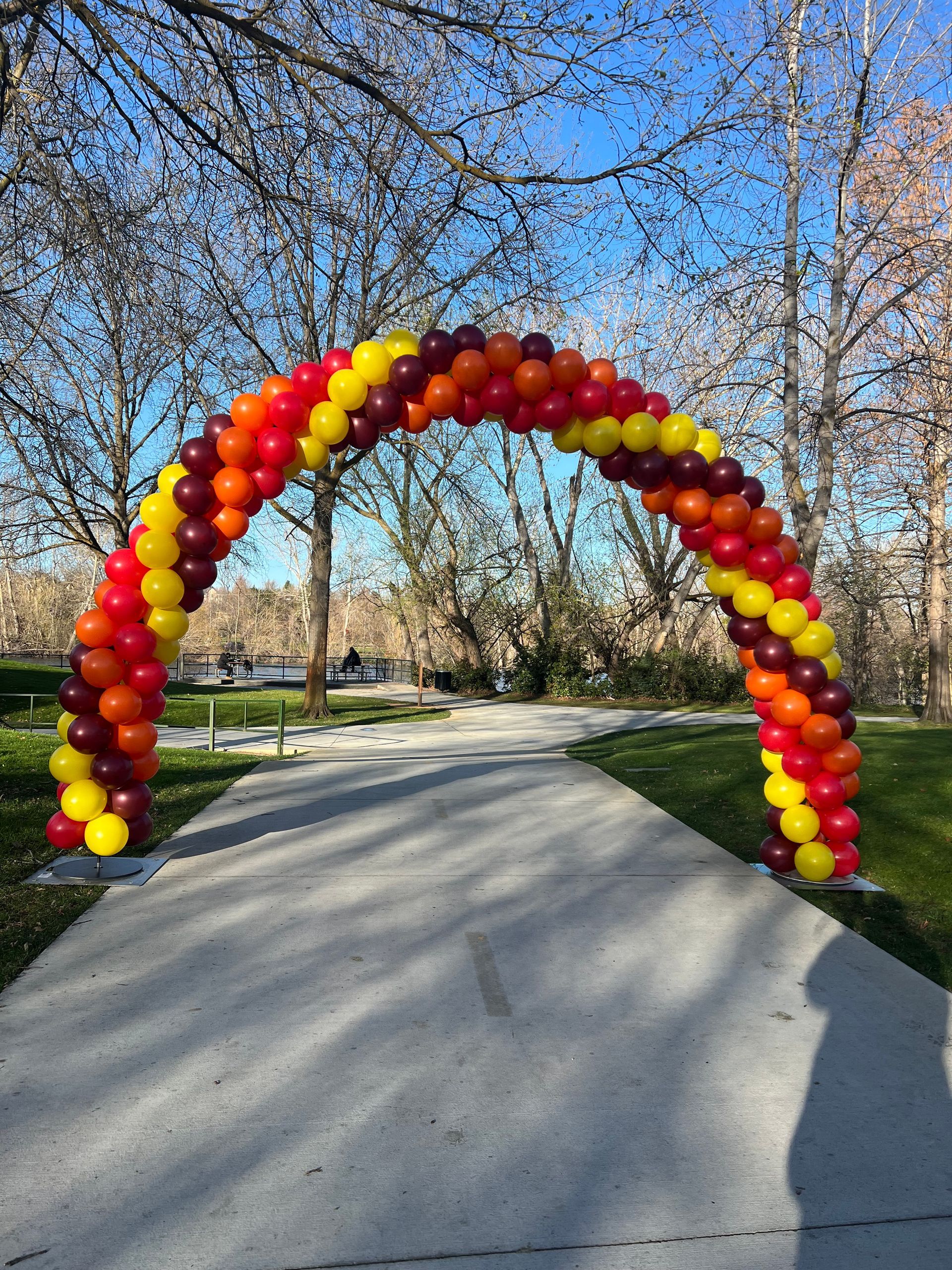 A large arch made of red , yellow and brown balloons