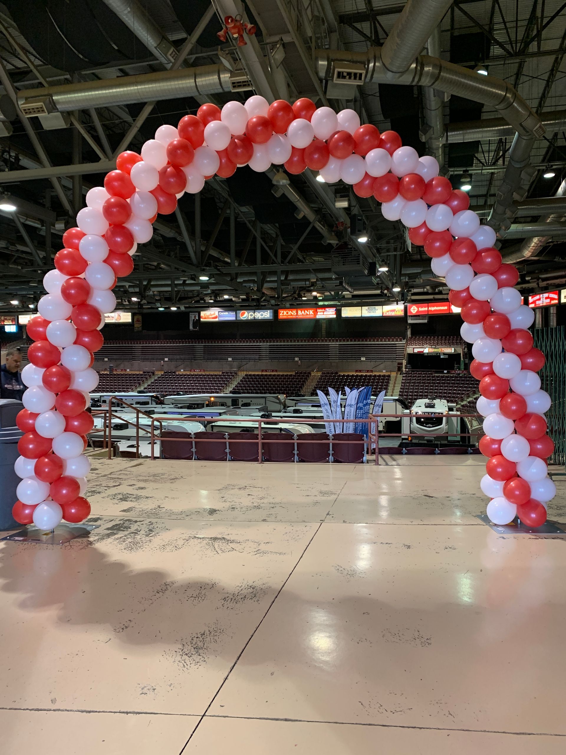 A red and white balloon arch in a stadium