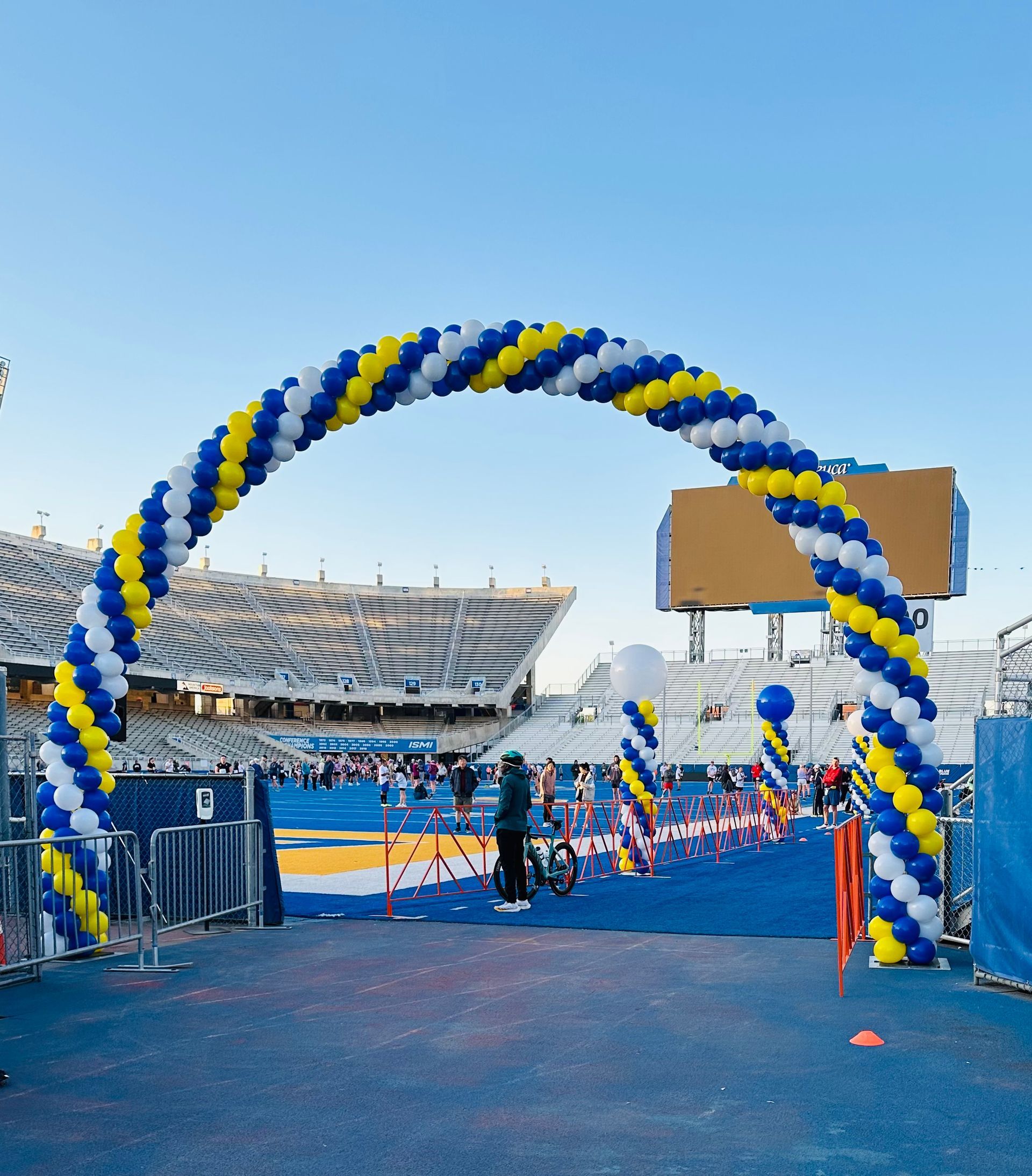 A blue and yellow balloon arch in front of a stadium