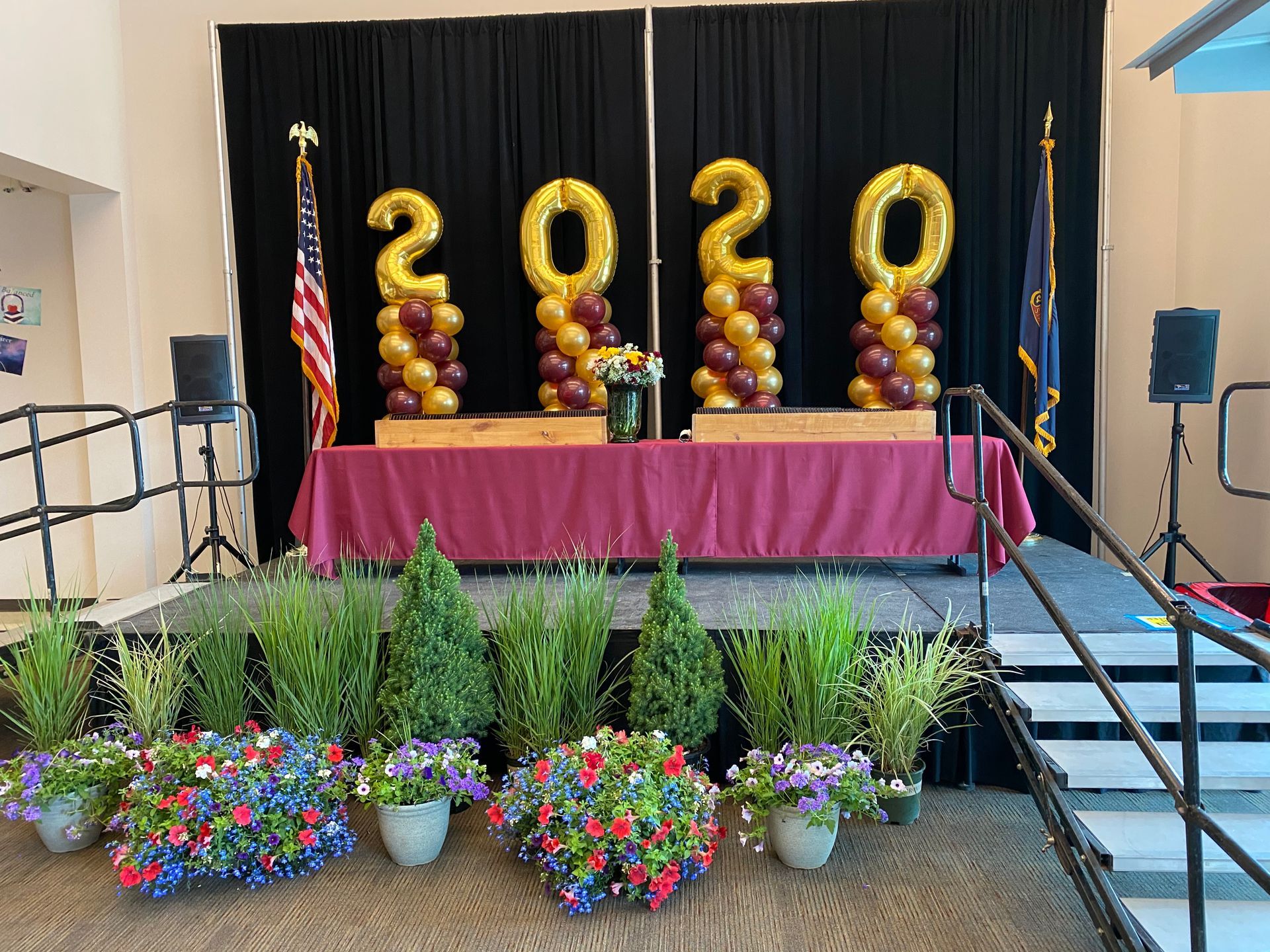 A stage decorated with balloons and flowers for a graduation ceremony.