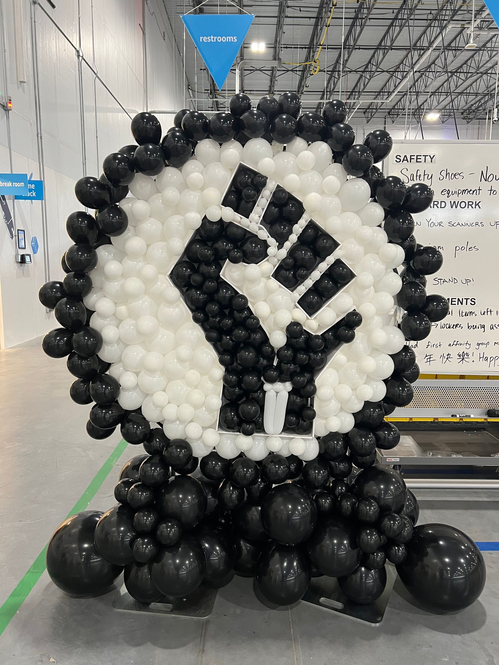 A fist made out of black and white balloons in a room.