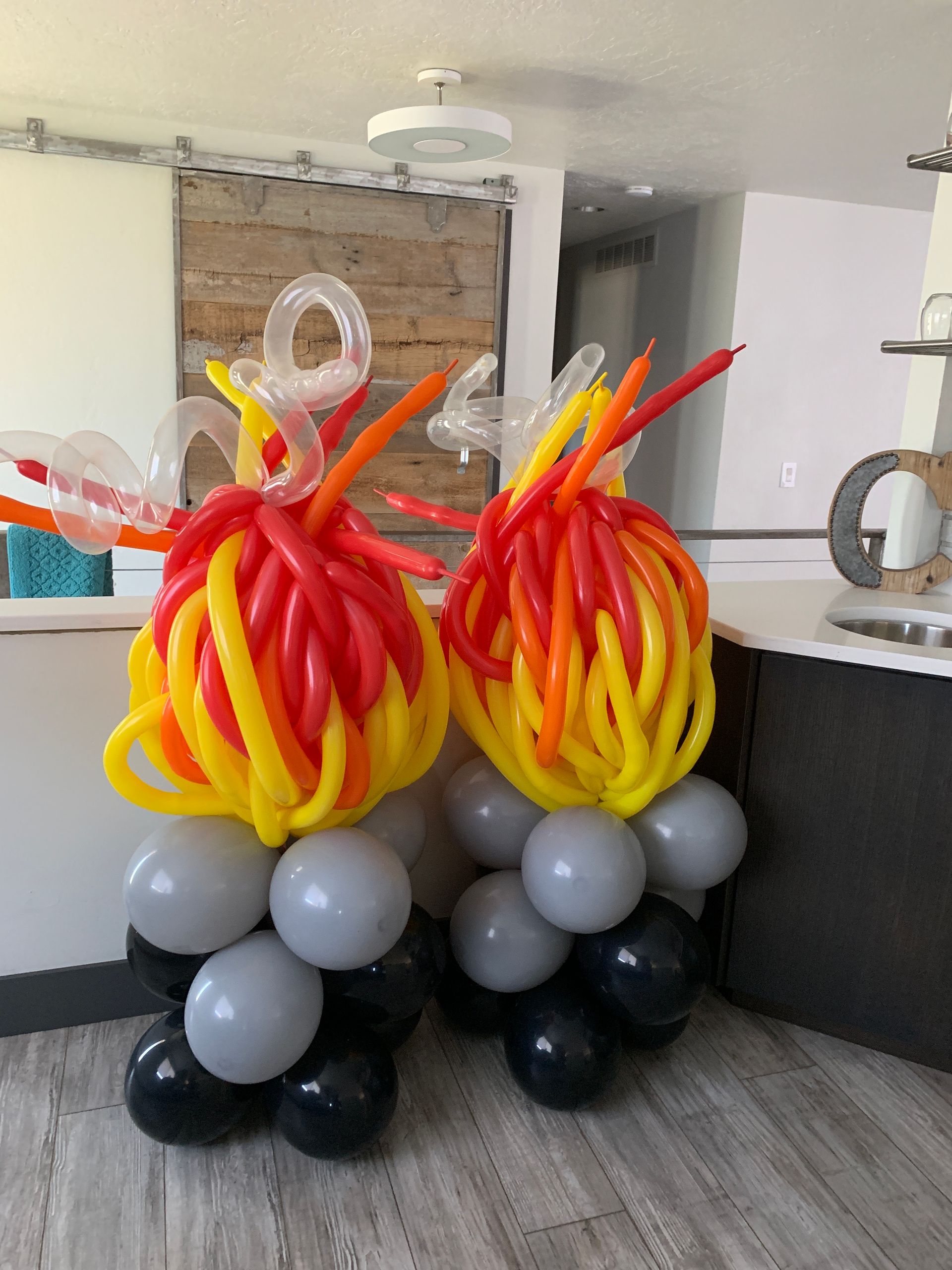 Two balloons made to look like fireballs are sitting on top of each other in a room.