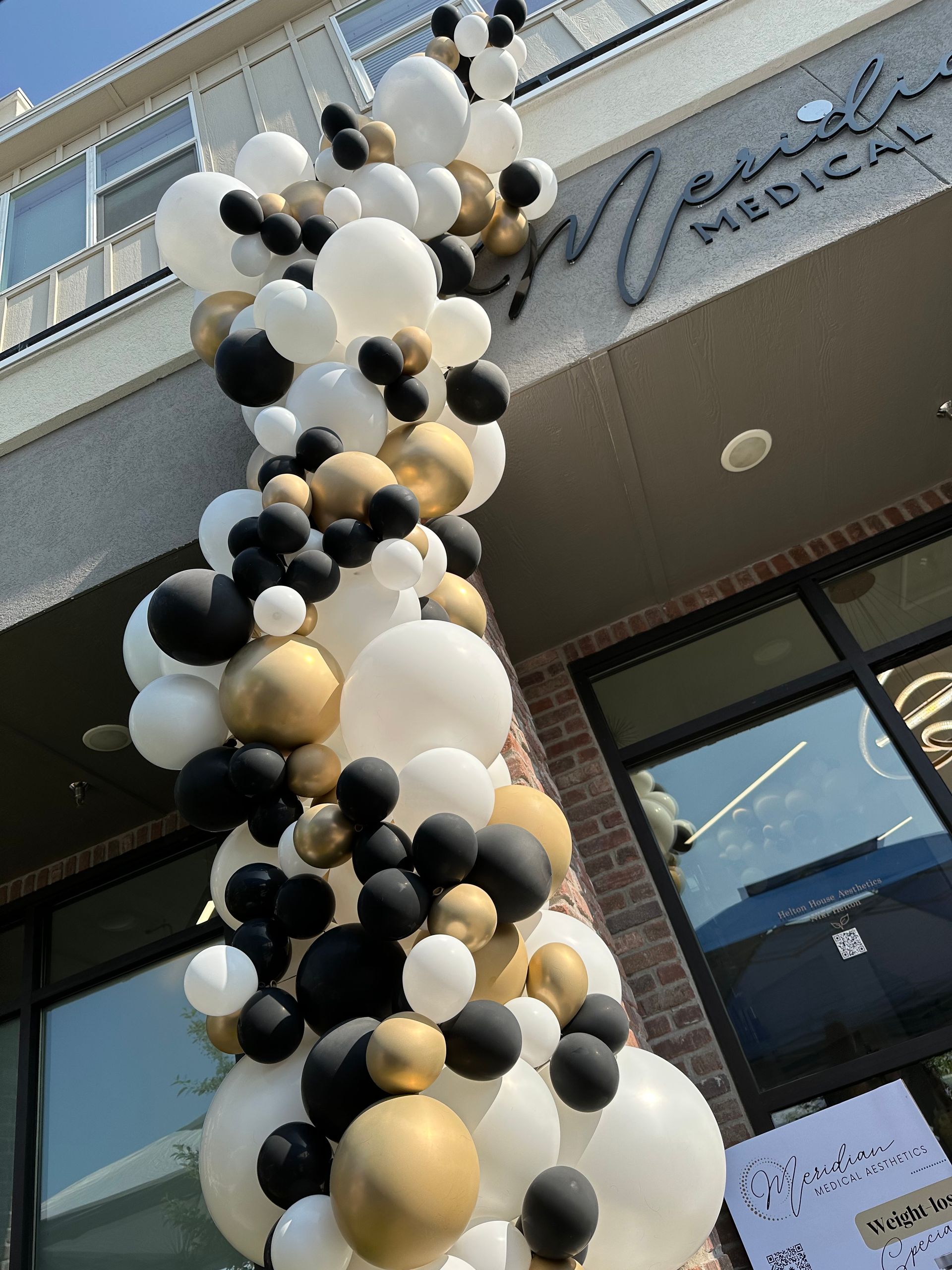 A bunch of black and white balloons are hanging from a building