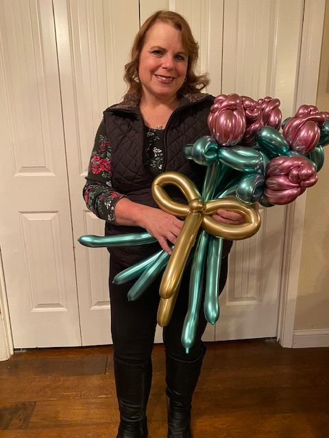 A woman is holding a bouquet of balloons that look like flowers.
