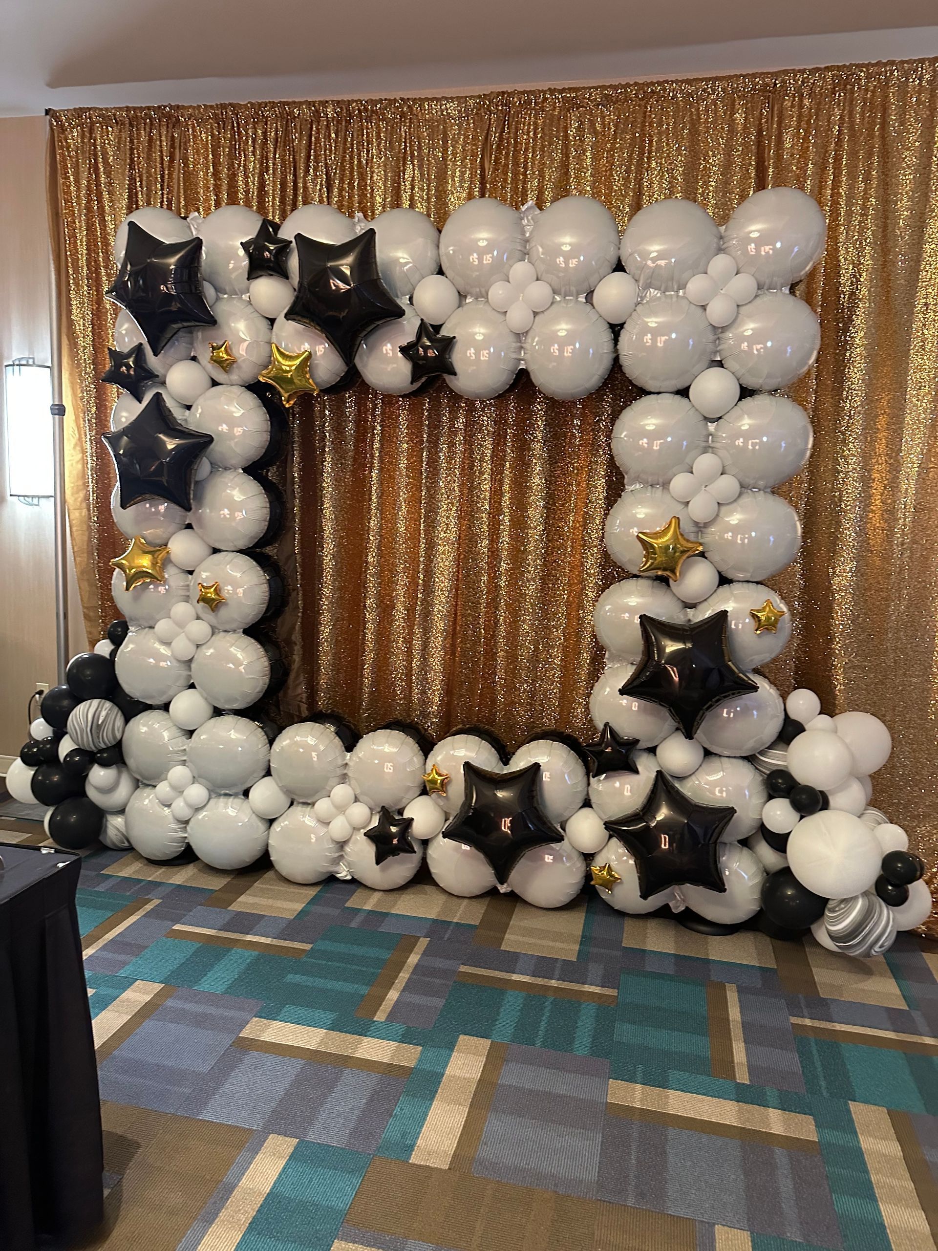 A room filled with balloons and a gold curtain.