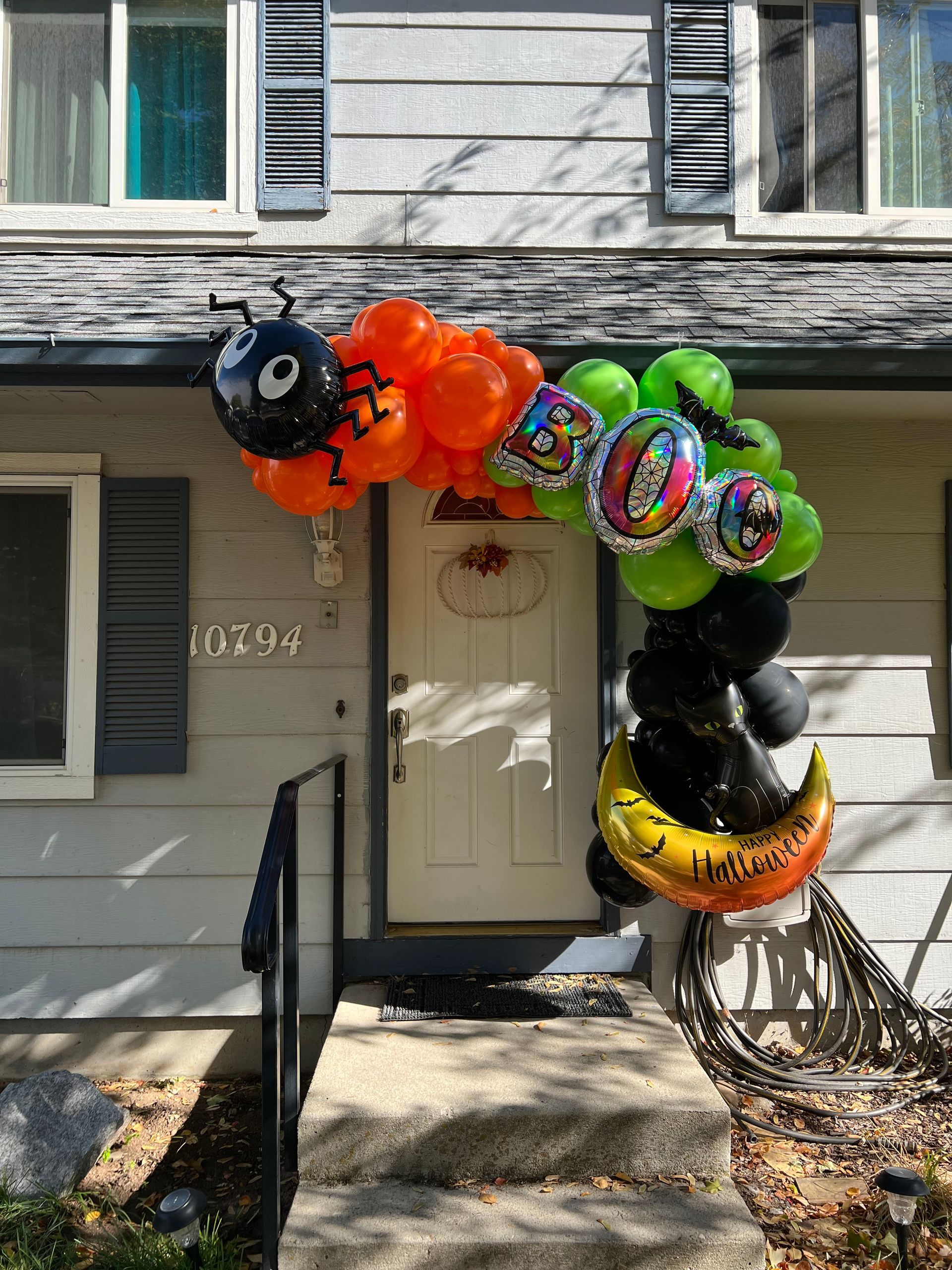 A house decorated for halloween with balloons and a spider on the front door.
