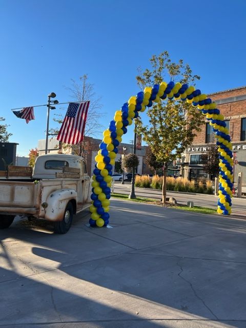 A truck is parked in front of a blue and yellow balloon arch