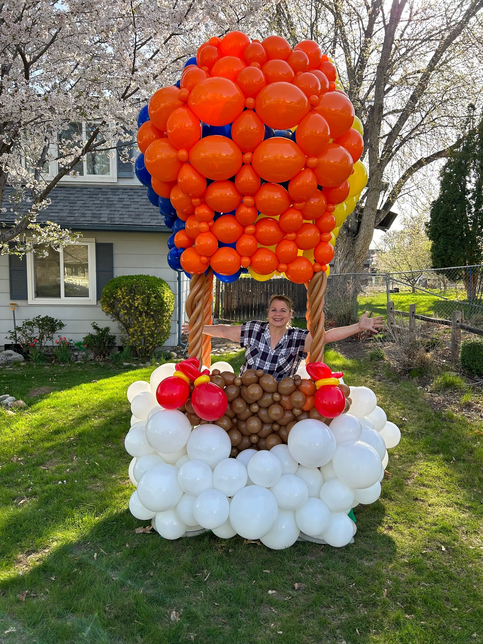 A woman is standing in front of a hot air balloon made of balloons.
