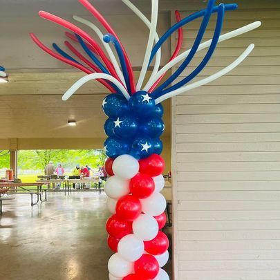A red , white , and blue balloon pillar in a room