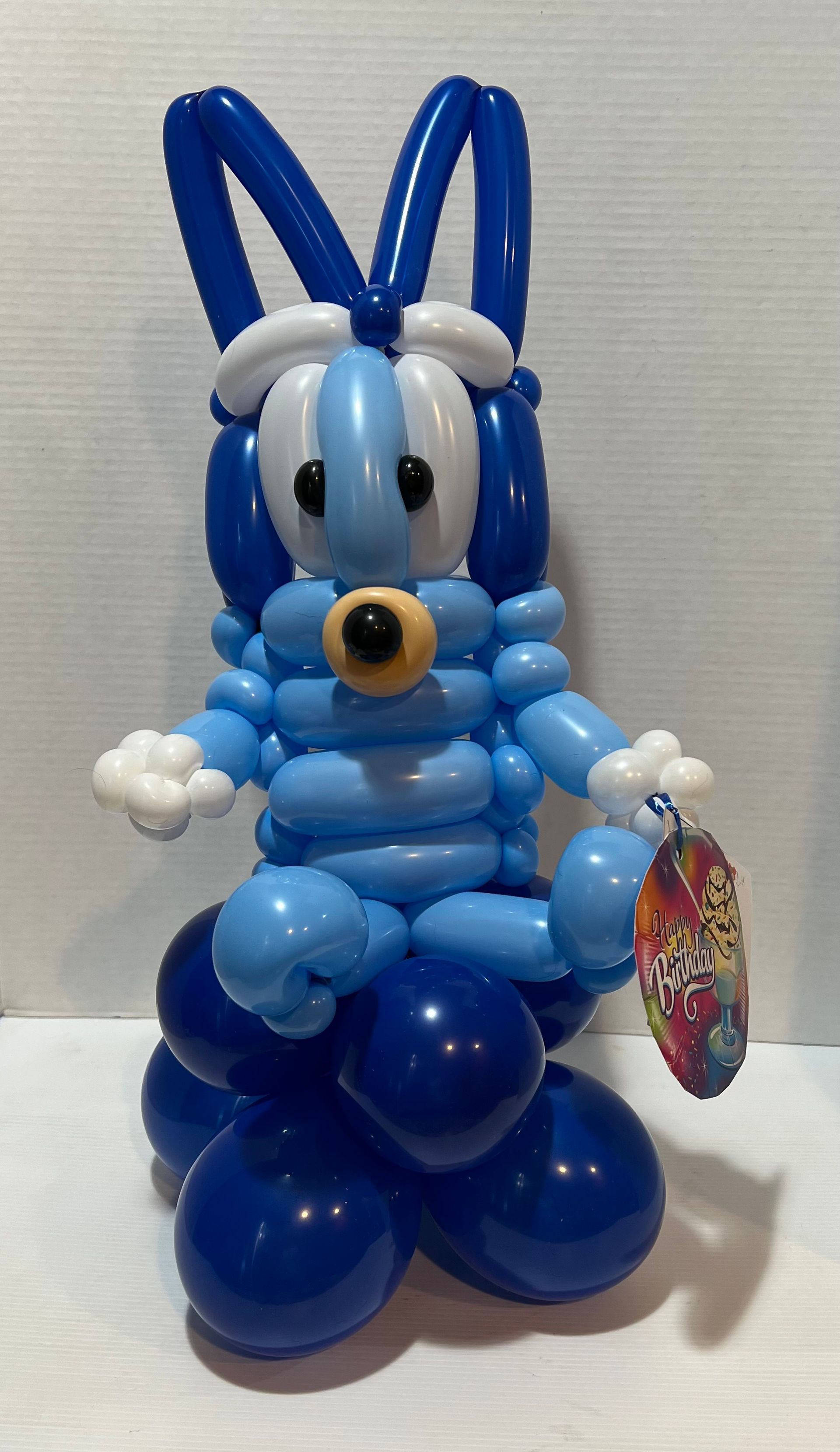 A blue and white balloon bunny is sitting on a table.