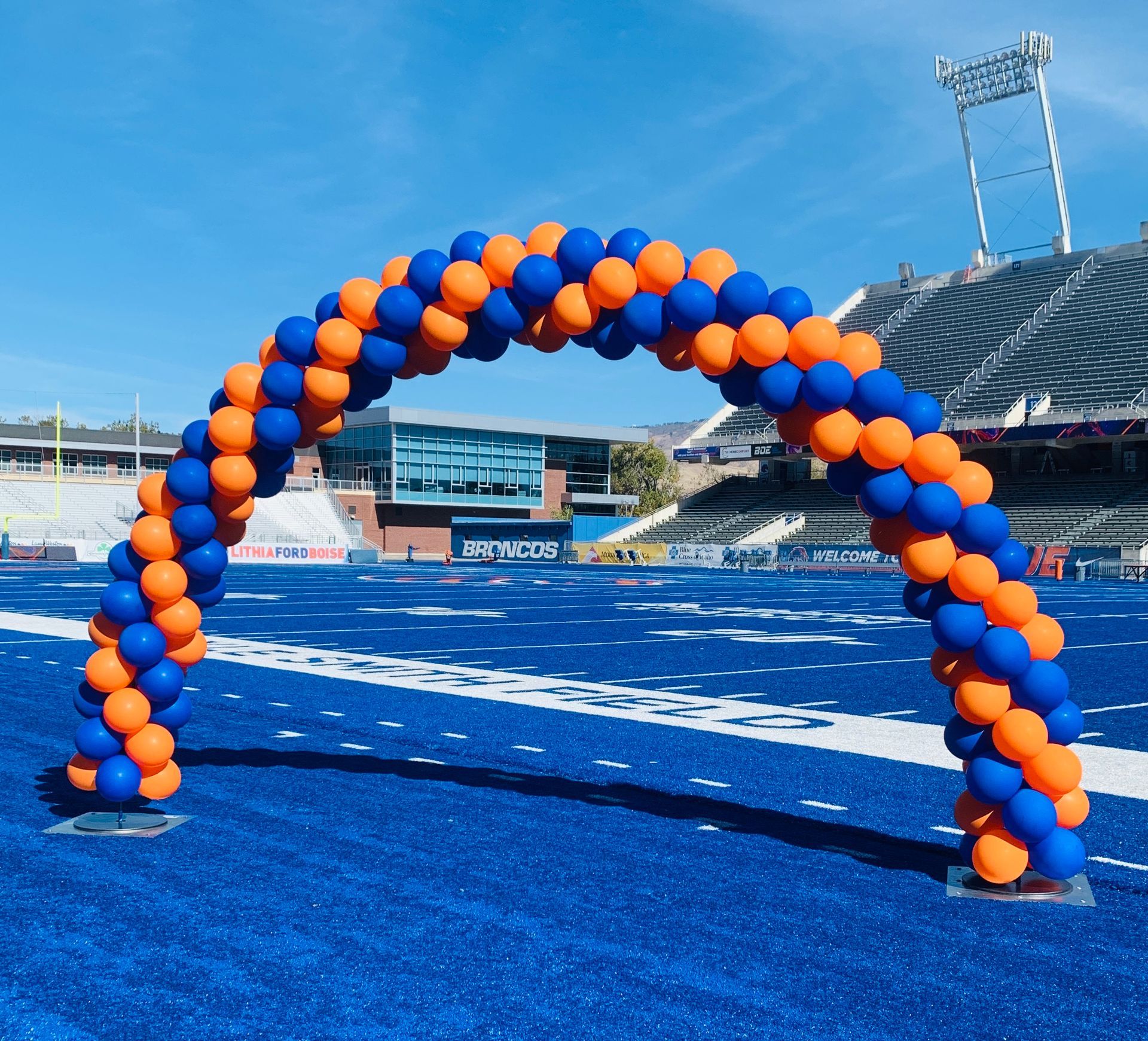 A blue and orange balloon arch on a football field